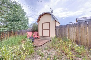 A small wooden shed with a door, surrounded by a wooden fence, and two red chairs in front. - Hike, Ski & Explore: Fraser Townhome w/ Hot Tub! (Fraser)