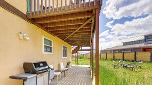 En overdækket terrasse med grill, stole og et bord.