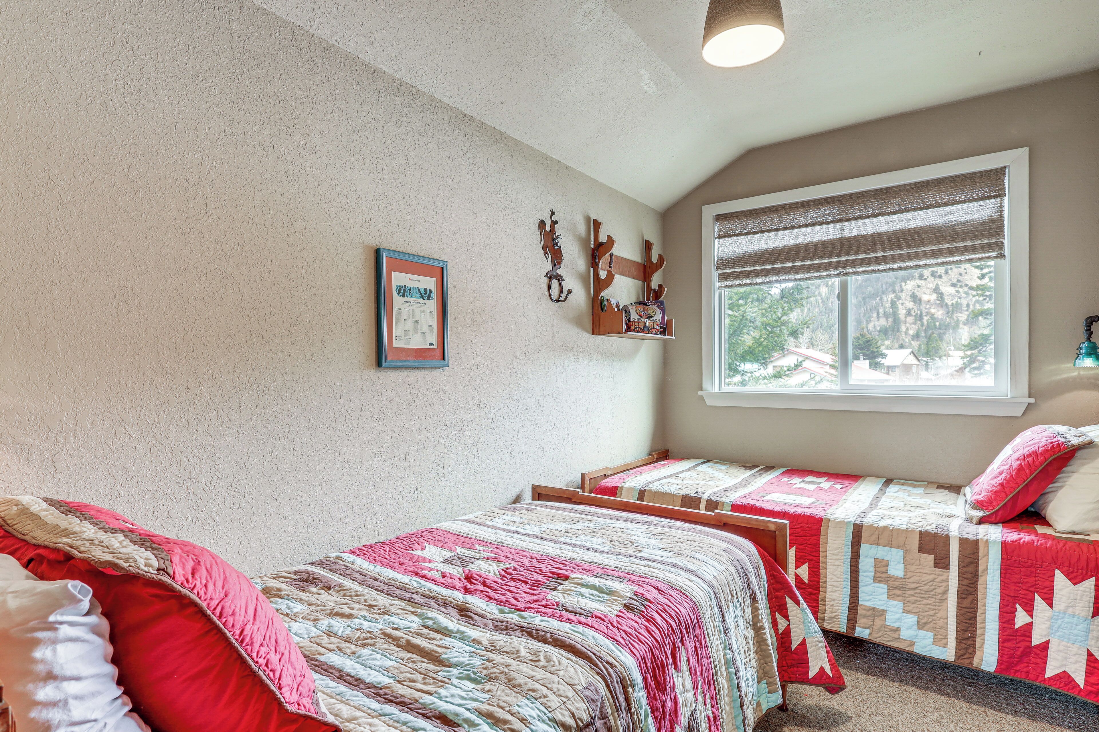 Une chambre avec deux lits, une fenêtre donnant sur un beau paysage et des décorations murales.