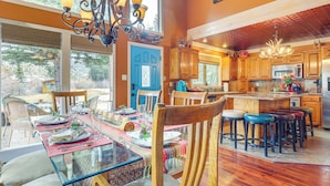 Una cocina amplia con armarios de madera, una isla central y un comedor con mesa y sillas de vidrio.