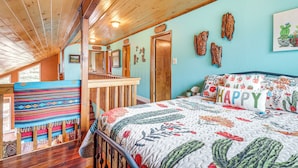 Un dormitorio con una cama, techo de madera y una ventana.