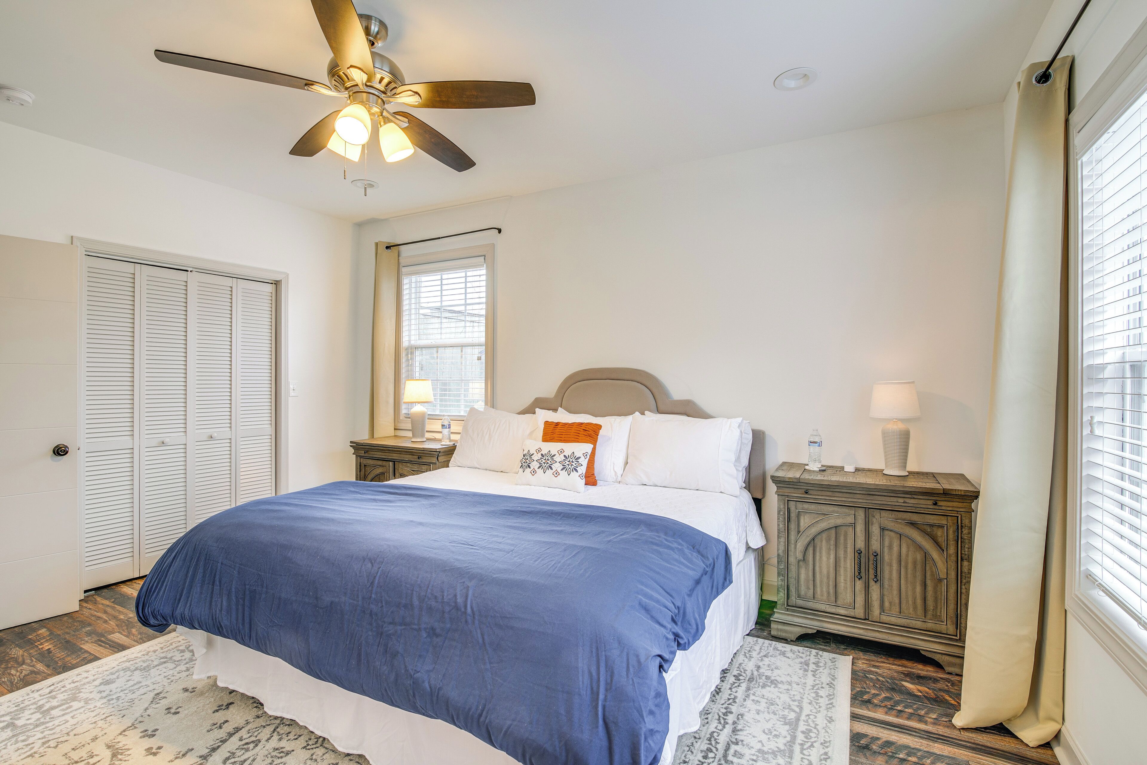 A bedroom with a bed, a nightstand, a dresser, a ceiling fan, and a window with blinds.