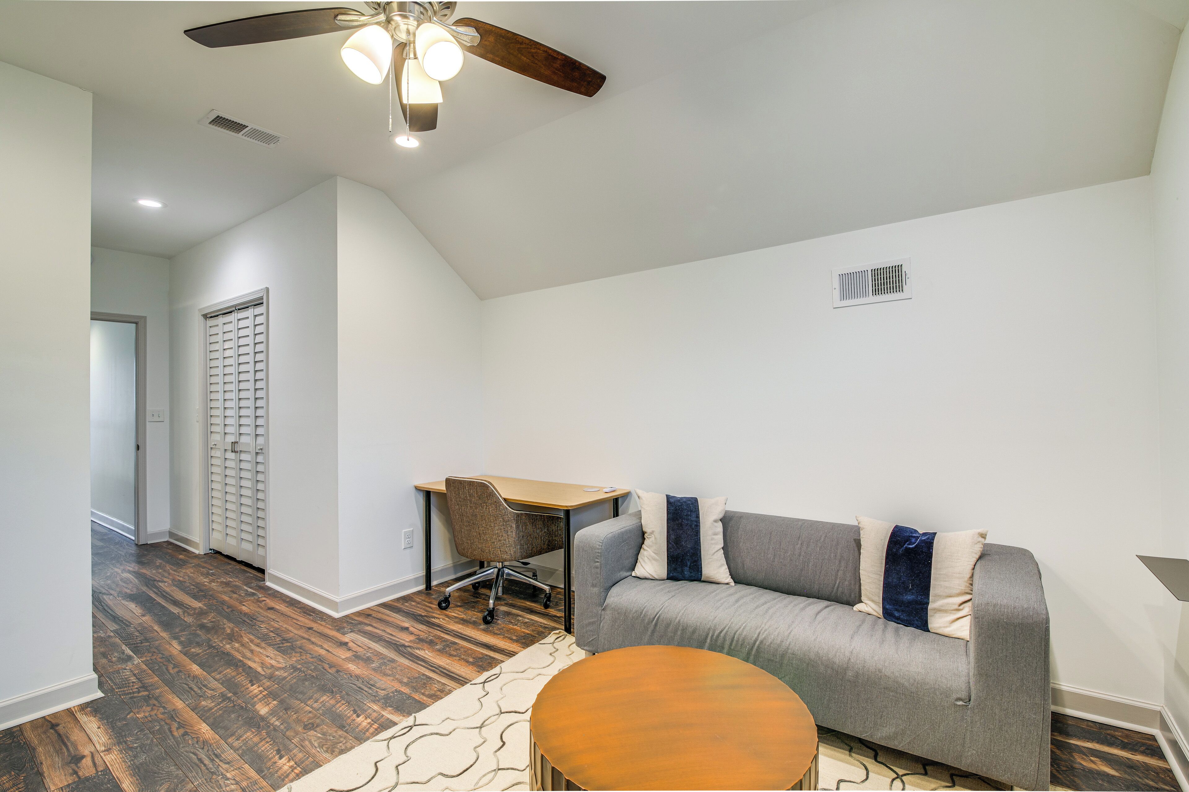 A modern living room with a gray sofa, wooden coffee table, and a ceiling fan.