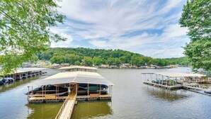 A lakeside dock with several covered boat docks and a wooden walkway leading to a boat. - Osage Beach Condo Pools, Boatslip and Pickleball (Osage Beach)