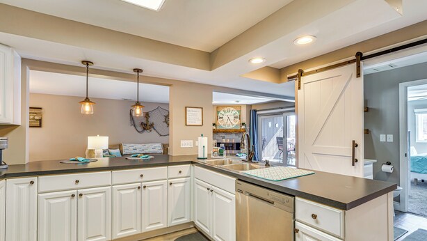 A modern kitchen with white cabinetry, a dishwasher, and pendant lighting. - Osage Beach Condo Pools, Boatslip and Pickleball (Osage Beach)