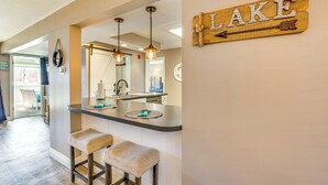A kitchen with a bar area, wooden wall decor, and a view into the dining area. - Osage Beach Condo Pools, Boatslip and Pickleball (Osage Beach)