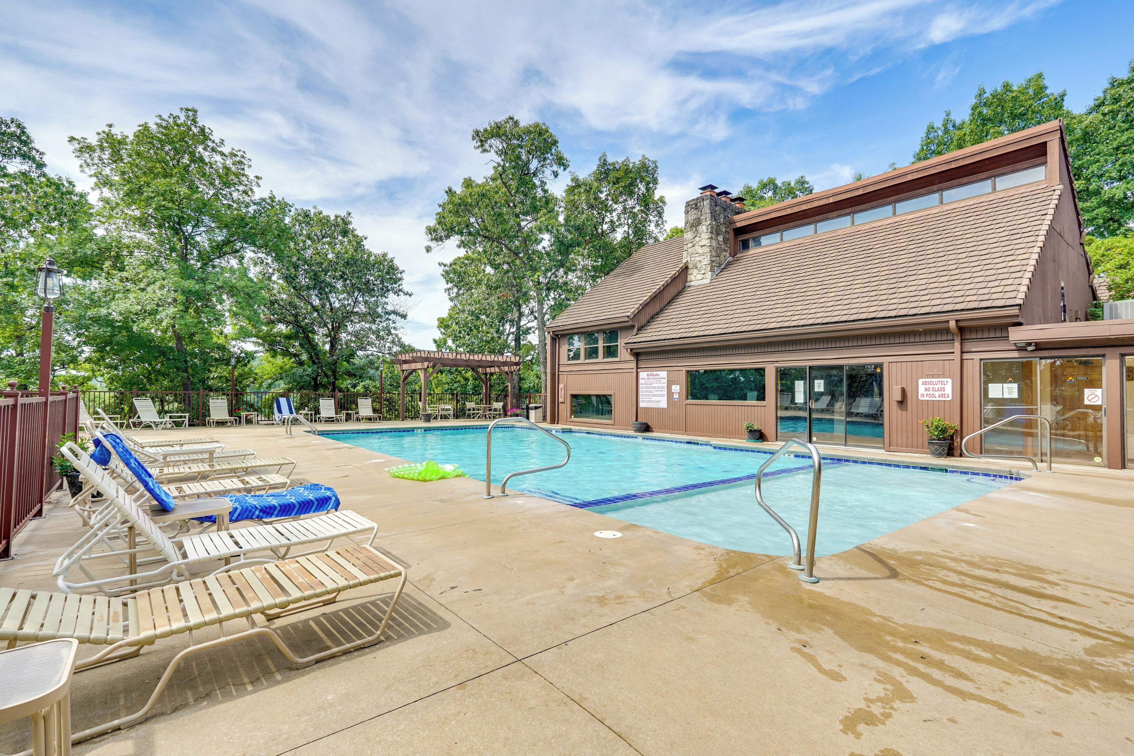 A pool area with lounge chairs and a building with a stone chimney.