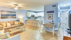 Une cuisine moderne avec des meubles blancs, un îlot central et un coin repas avec des chaises blanches.