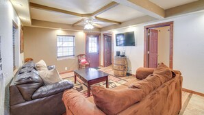 A living room with a brown leather couch, a wooden coffee table, and a ceiling fan. There is a wooden barrel and a television on the wall. - Near Riding Trails for Atvs: Cabin in Delbarton (Delbarton)