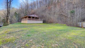 A cabin with a wooden deck and a fenced yard surrounded by trees. - Near Riding Trails for Atvs: Cabin in Delbarton (Delbarton)