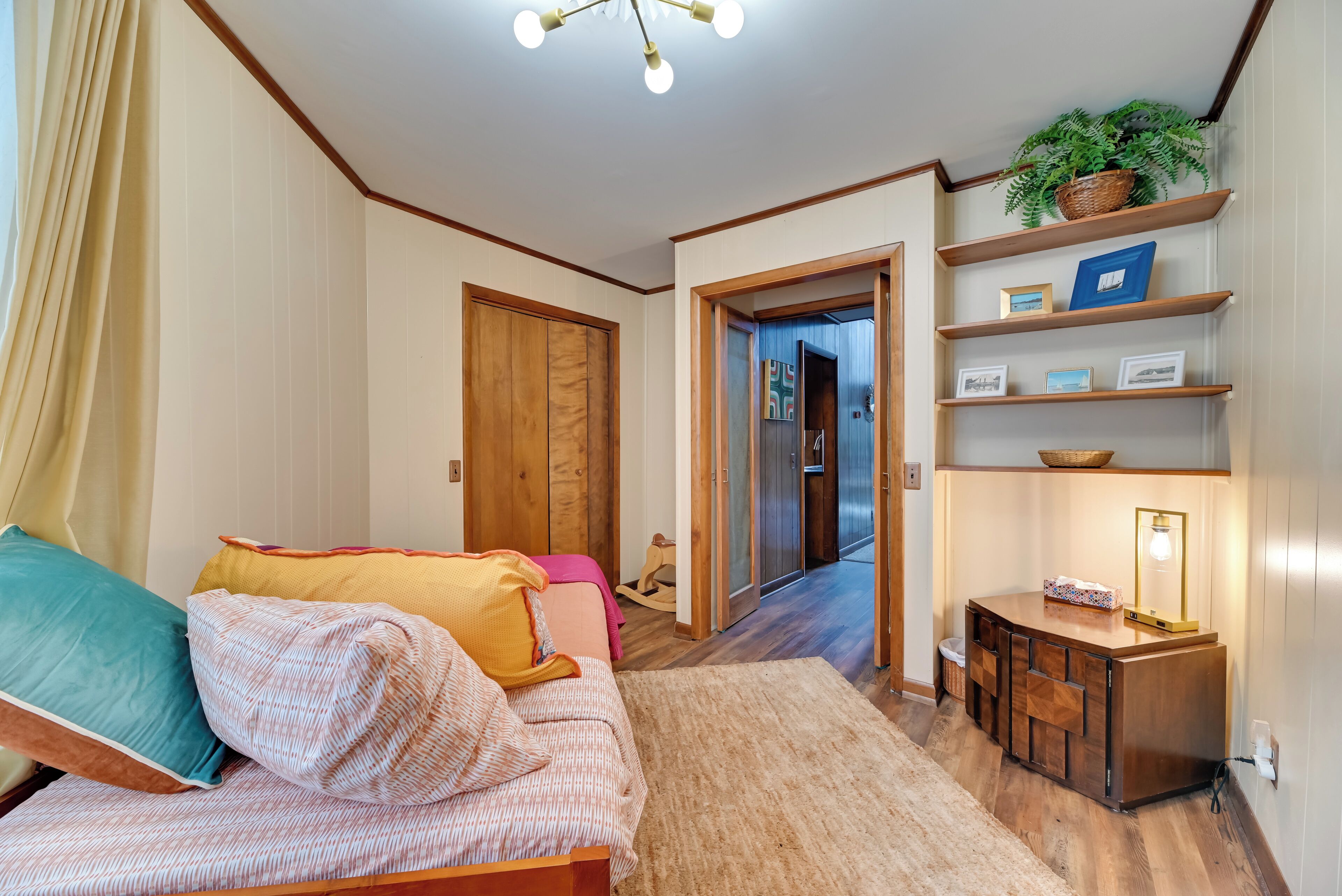A cozy living room with a sofa, a small wooden cabinet, and a hallway leading to another room.