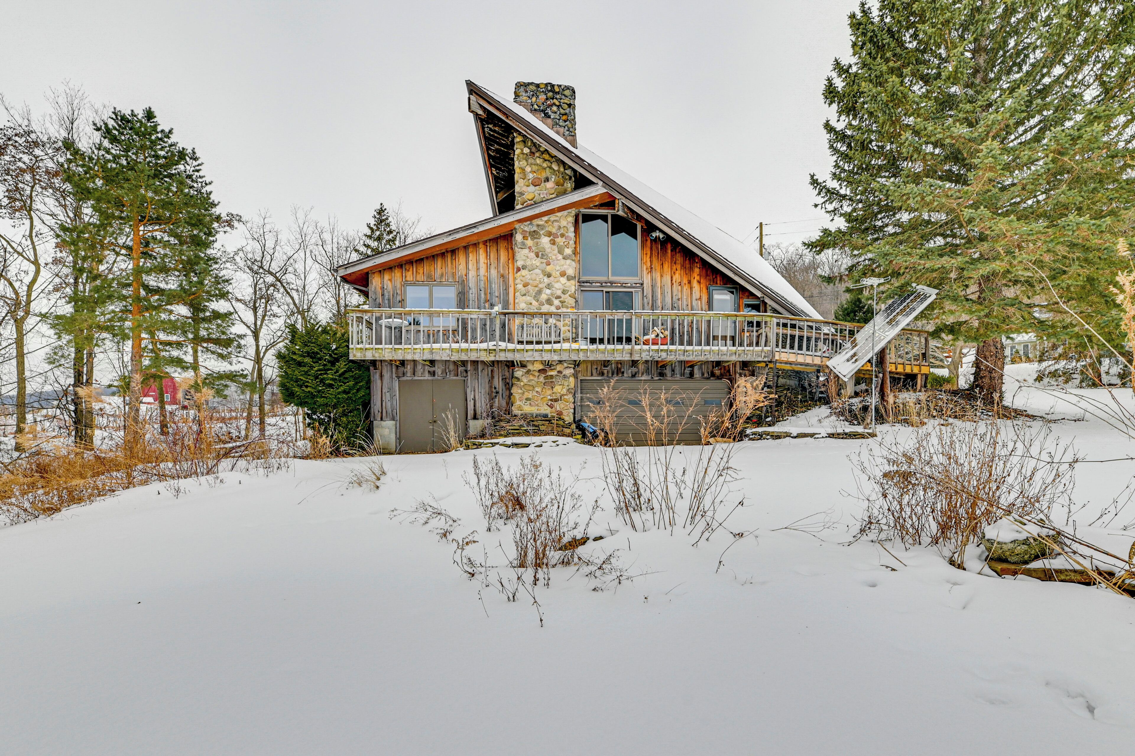 Une cabane à la façade en pierre, avec une terrasse en bois et un toit en pente.