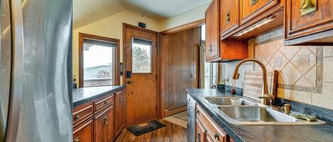 A kitchen with wooden cabinets, a stainless steel refrigerator, a sink, and a window.
