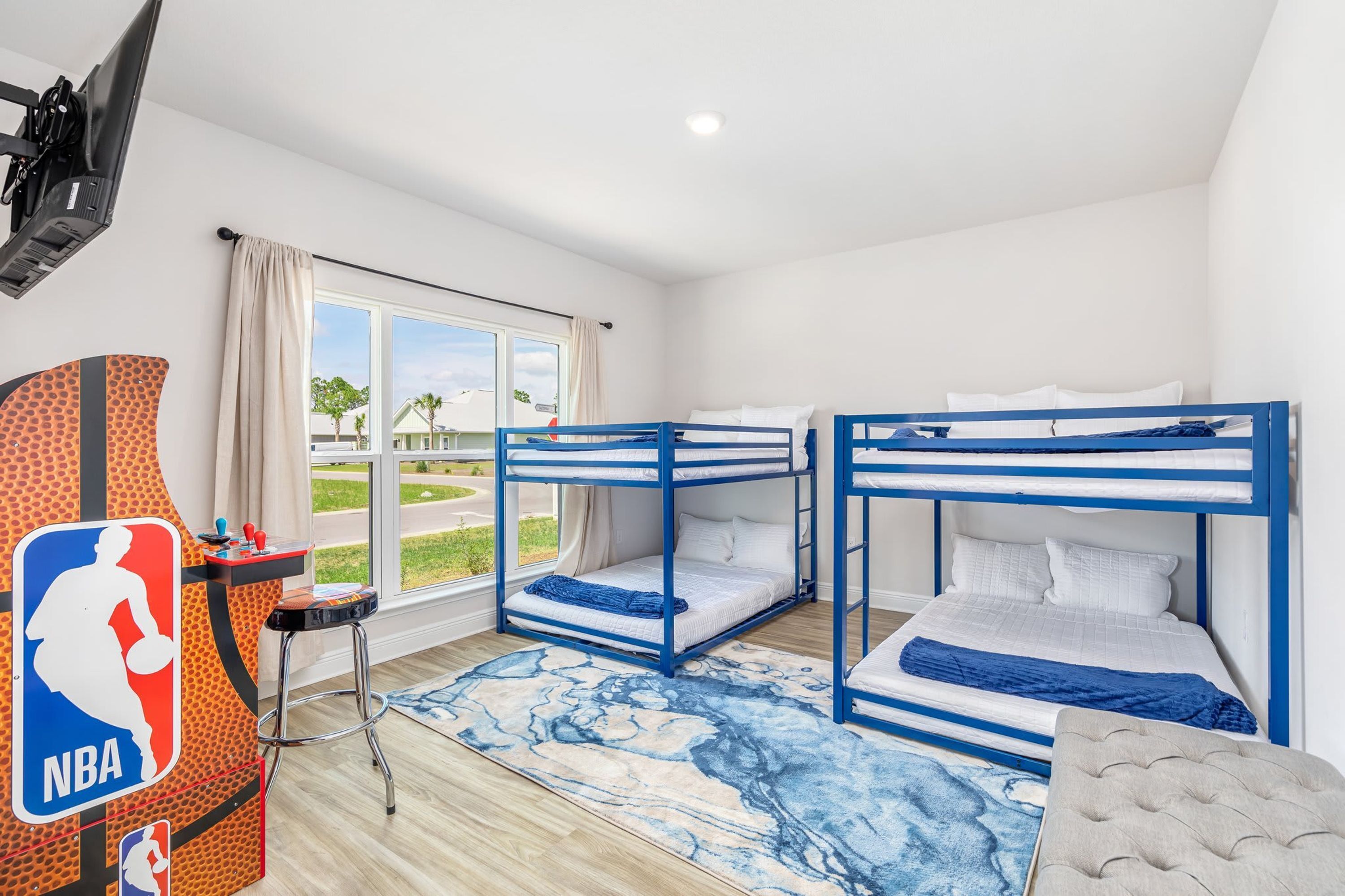 Quarto com beliches, decoração com tema de basquete, uma janela grande e vista para o exterior.