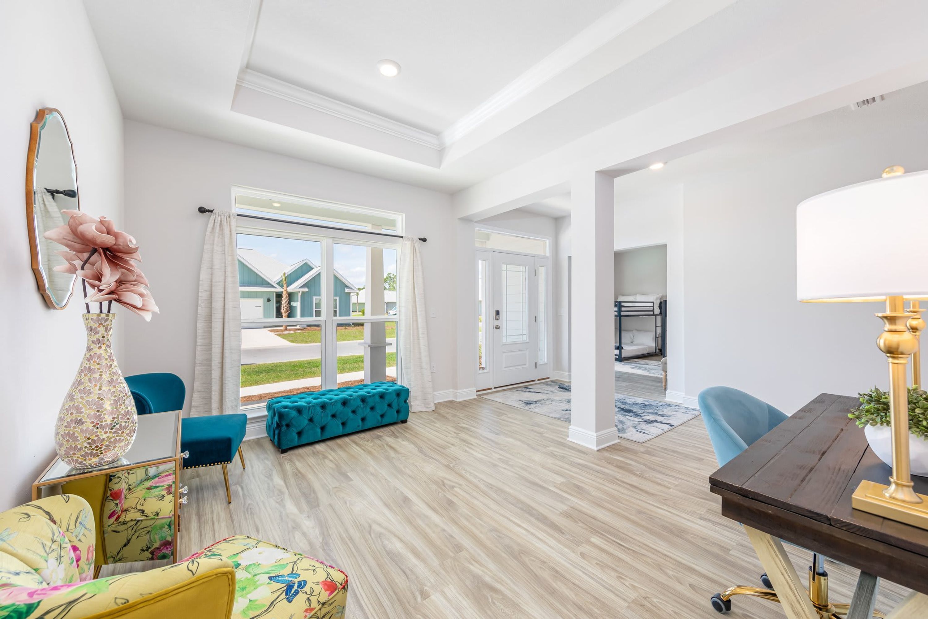 Un salon spacieux doté d’un plancher en bois, d’une grande fenêtre et d’un canapé de couleur turquoise.