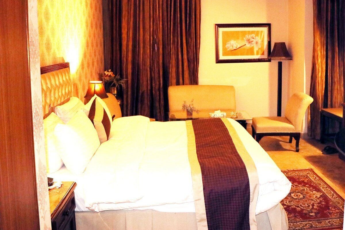 Habitación de hotel con una cama grande, una silla, un escritorio y un cuadro en la pared.
