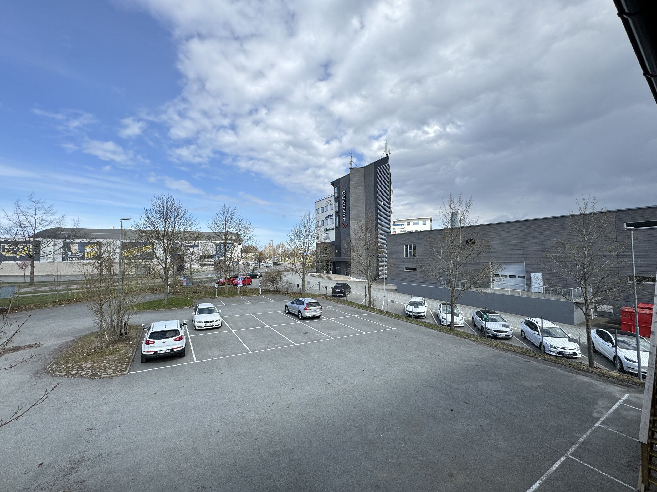 A parking lot with several cars, a building with a modern design, and a clear sky.