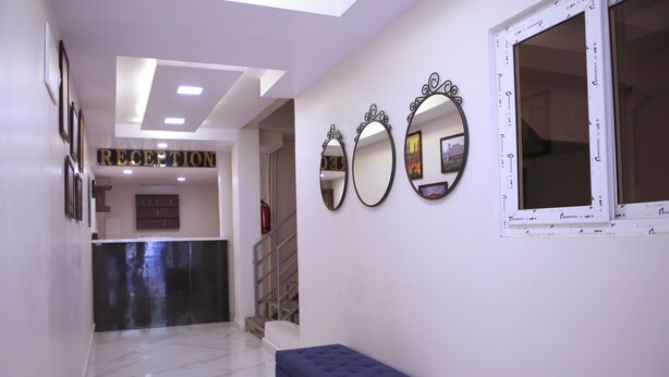 A reception area with a marble floor, a blue bench, and three wall mirrors. - PSV Grand (Hyderabad)