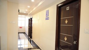 A hotel corridor with a marble floor, wooden doors, and a sign indicating the third floor. - PSV Grand (Hyderabad)