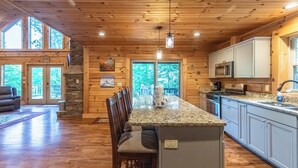 Un'ampia cucina con pavimento in legno, piani in granito e un'isola centrale.