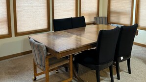 A dining room with a large wooden table, six chairs, and large windows with blinds. - Hot tub, Pet friendly, directly across from GM Rec Center (Black Butte Ranch)