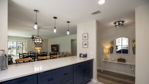 A modern kitchen with dark blue cabinets, a white countertop, pendant lights, and a large window. - 25 Springwood: First Floor, 1 Level, Walk to Beach (Hilton Head Island)