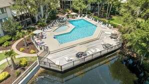 A rectangular swimming pool with a deck surrounding it, connected to a body of water by a bridge. - 25 Springwood: First Floor, 1 Level, Walk to Beach (Hilton Head Island)