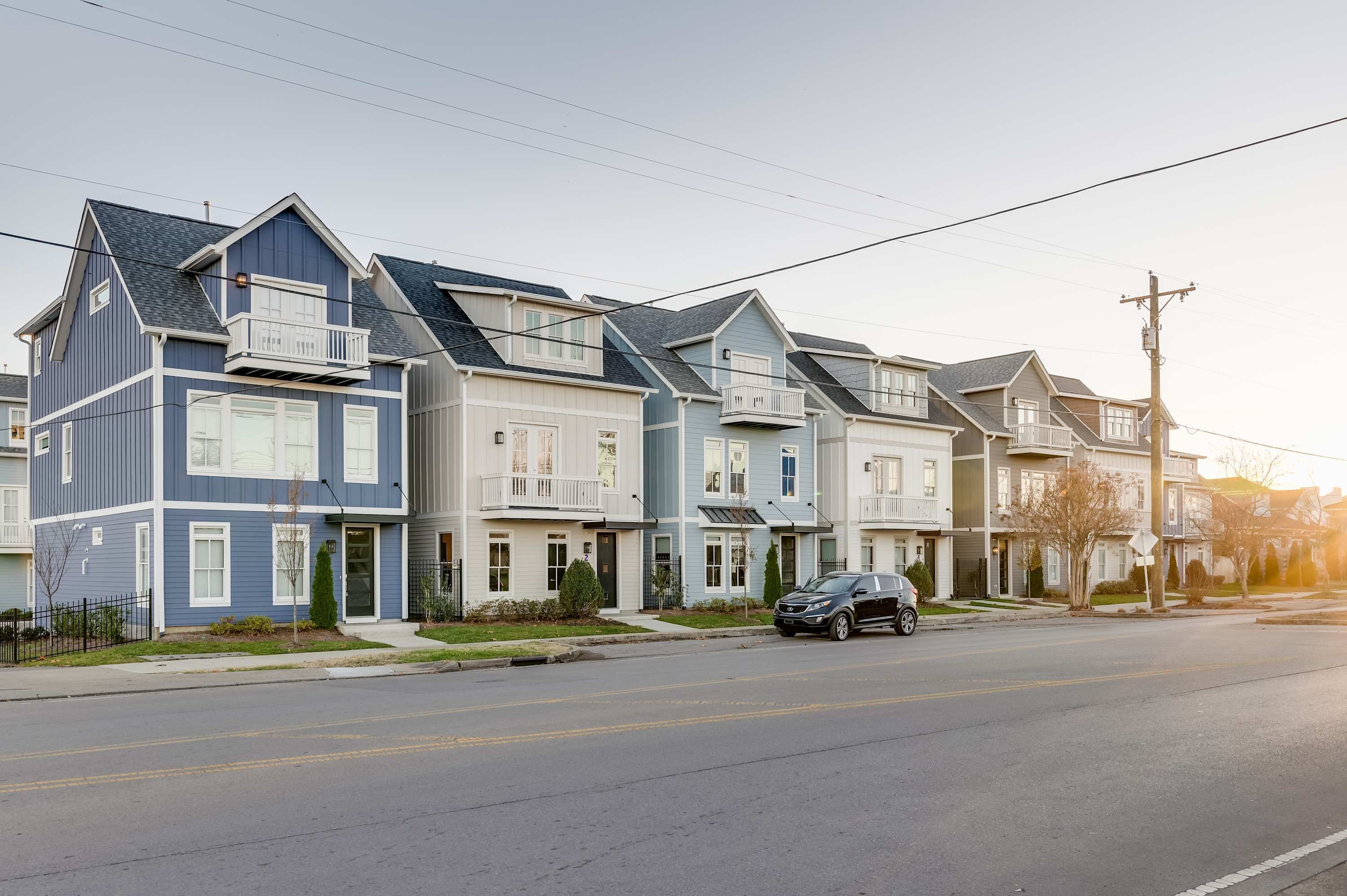 A row of townhouses with a garage, a small front yard, and a street view.