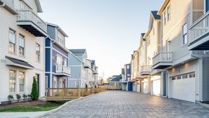 En bostadsgata med moderna hus, asfalterade trottoarer och en klar himmel.