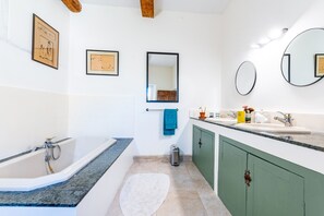 Bathroom features a bathtub, large mirror, and vanity with sink.
