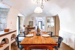 Enjoy meals in this cozy dining area with a rustic table for four, black chairs, and a chandelier.