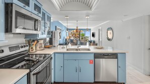 Una cocina moderna con armarios azules, electrodomésticos de acero inoxidable y una isla central con un fregadero.