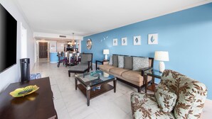 Una sala de estar con una pared azul, un sofá, una mesa de centro y un televisor.