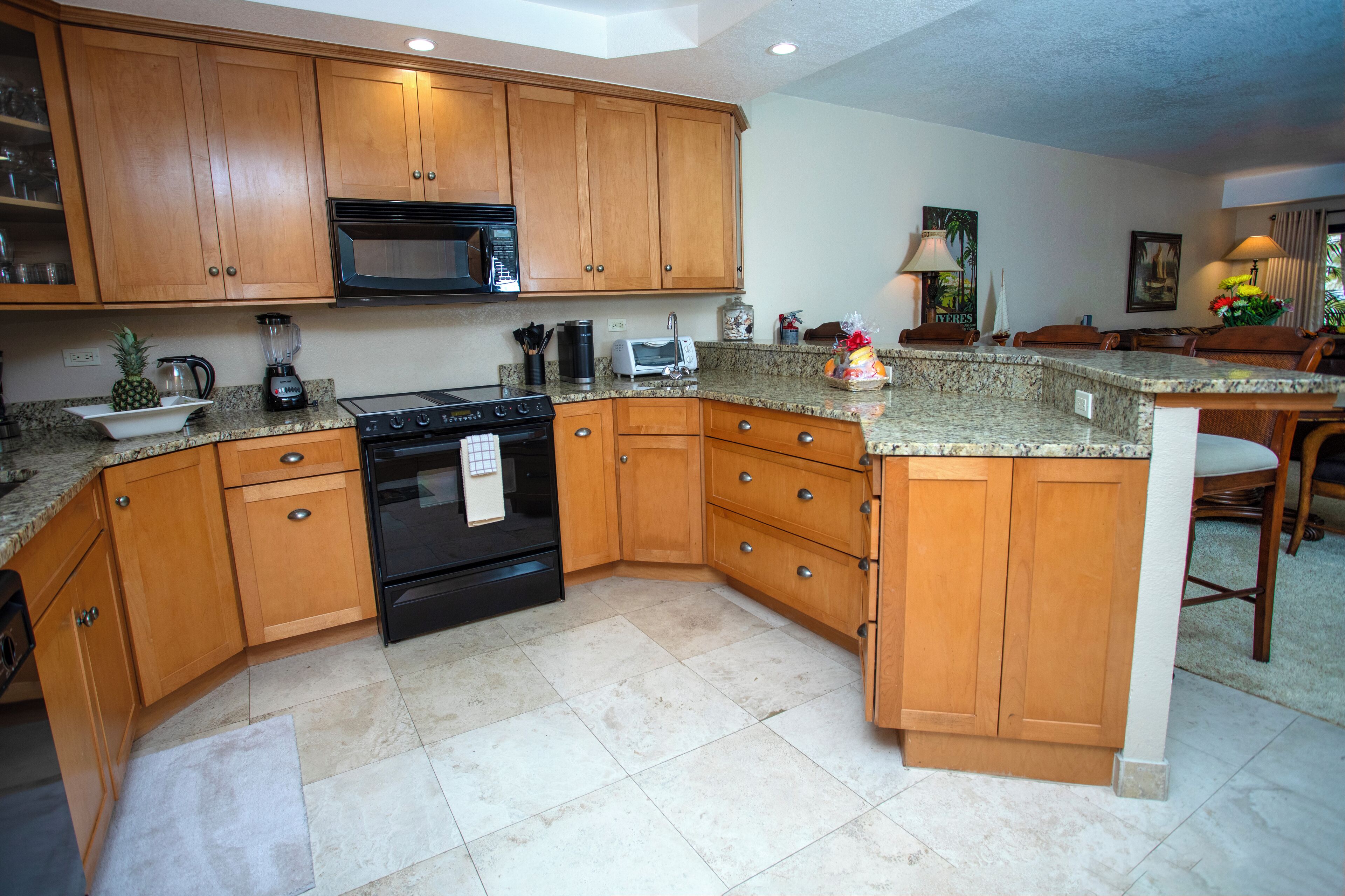 A kitchen with wooden cabinets, a microwave, stove, and granite countertops.
