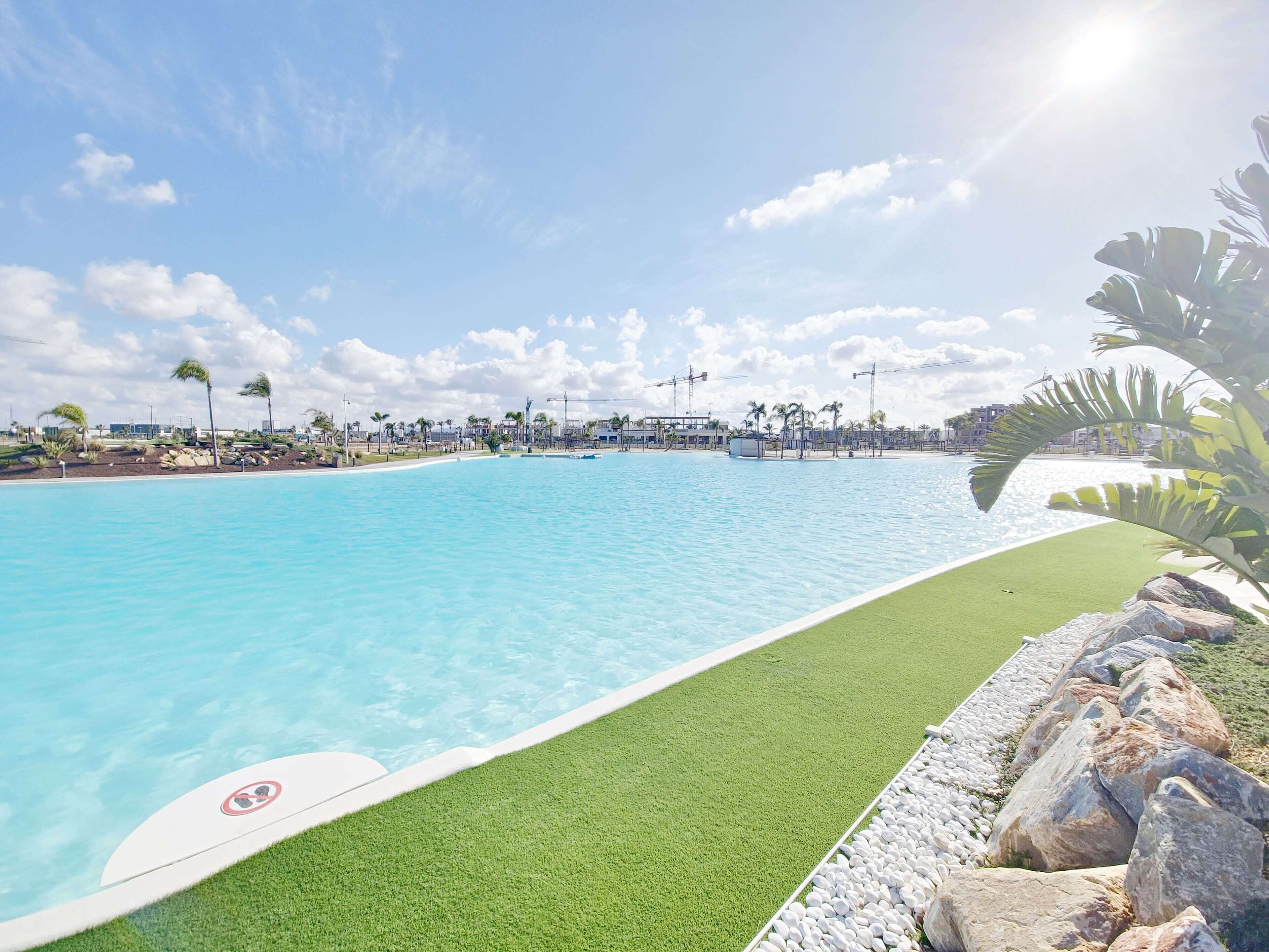 Ein großer Pool mit einer Rasenfläche und Felsen am Rand.