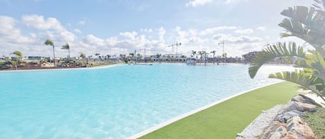 A large swimming pool with a grassy area and rocks along the edge.