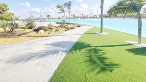 A pathway leading to a pool area with artificial grass and palm trees. - Exclusive Penthouse in Santa Rosalia Lake & Life Resort El Caribe on the Costa Calida (Torre-Pacheco)