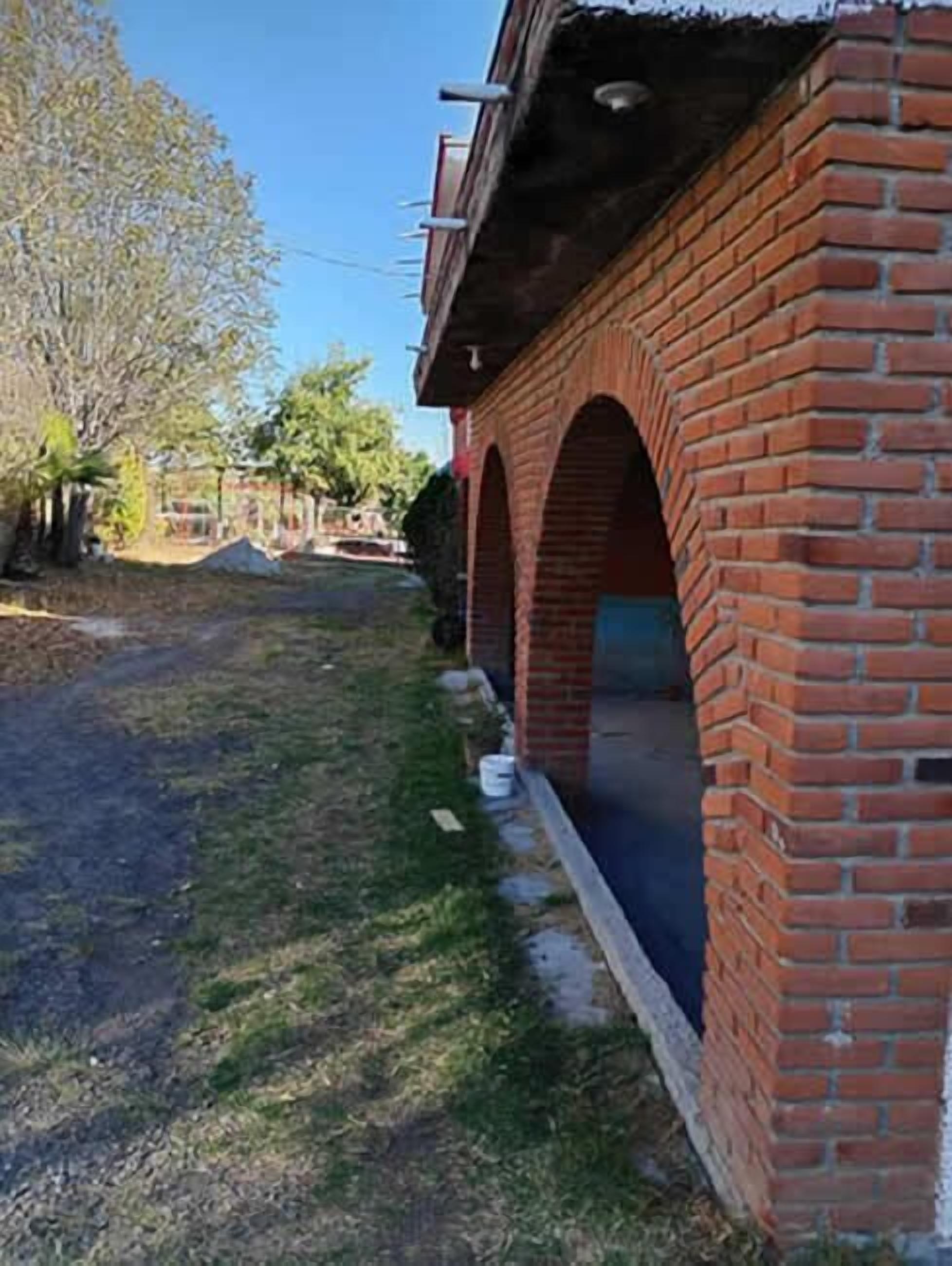 Un edificio de ladrillo con un corredor cubierto y cielo despejado.