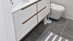 A modern bathroom with two sinks, a toilet, and a shower. - Luxury apartment 25m from the island's most beautiful beach, Boucan Canot. (Saint-Paul)