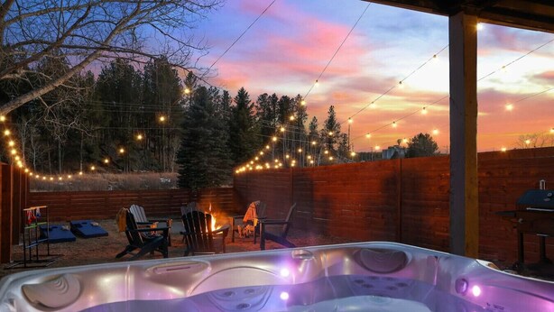 Un bain à remous avec vue sur le coucher de soleil, entouré d’espaces de détente en plein air et illuminé de guirlandes lumineuses.