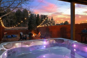 A hot tub with a sunset view, surrounded by outdoor seating and string lights. - Hot Tub Hideout | Private + Downtown Access (Custer)