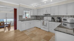 Et moderne køkken med hvide skabe, et flisebeklædt bagpanel og rustfrie stålapparater.