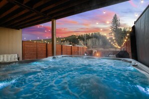 A hot tub under a wooden pergola with a sunset view, surrounded by a wooden fence and string lights. - Buffalo Ridge | Hot Tub + Walk to Downtown (Custer)