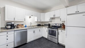 Una cocina moderna con armarios blancos, electrodomésticos de acero inoxidable y encimera de granito.