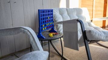 A blue game board with colorful pegs, a small round table, and two white cushioned chairs.