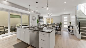 A modern kitchen with a large island, built-in appliances, and pendant lighting.