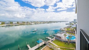 A waterfront view with a dock, a boat, and a pool area. - Wind Drift 615n 2 Bedroom Condo (Orange Beach)