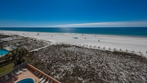 Vista a la playa con zona de piscina, área cercada y cielo despejado.