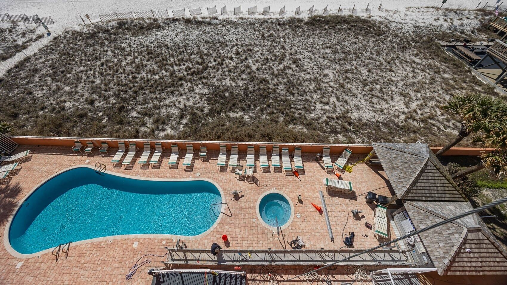 Uma área de piscina no terraço, com duas piscinas, espreguiçadeiras e vista para a praia.