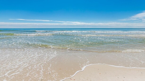 Ein Strand mit klarem, blauem Wasser und einem sandigen Ufer.